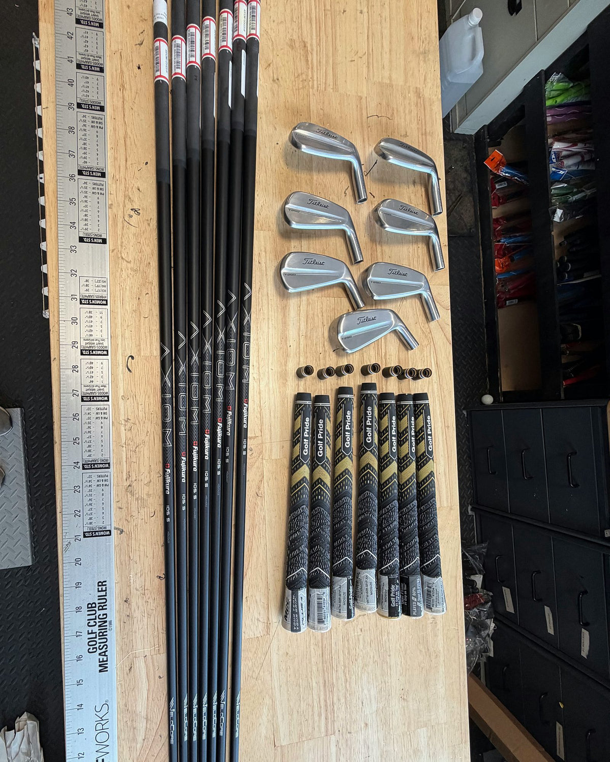 Shafts, iron heads and grips for one set next to the measuring ruler on the workbench